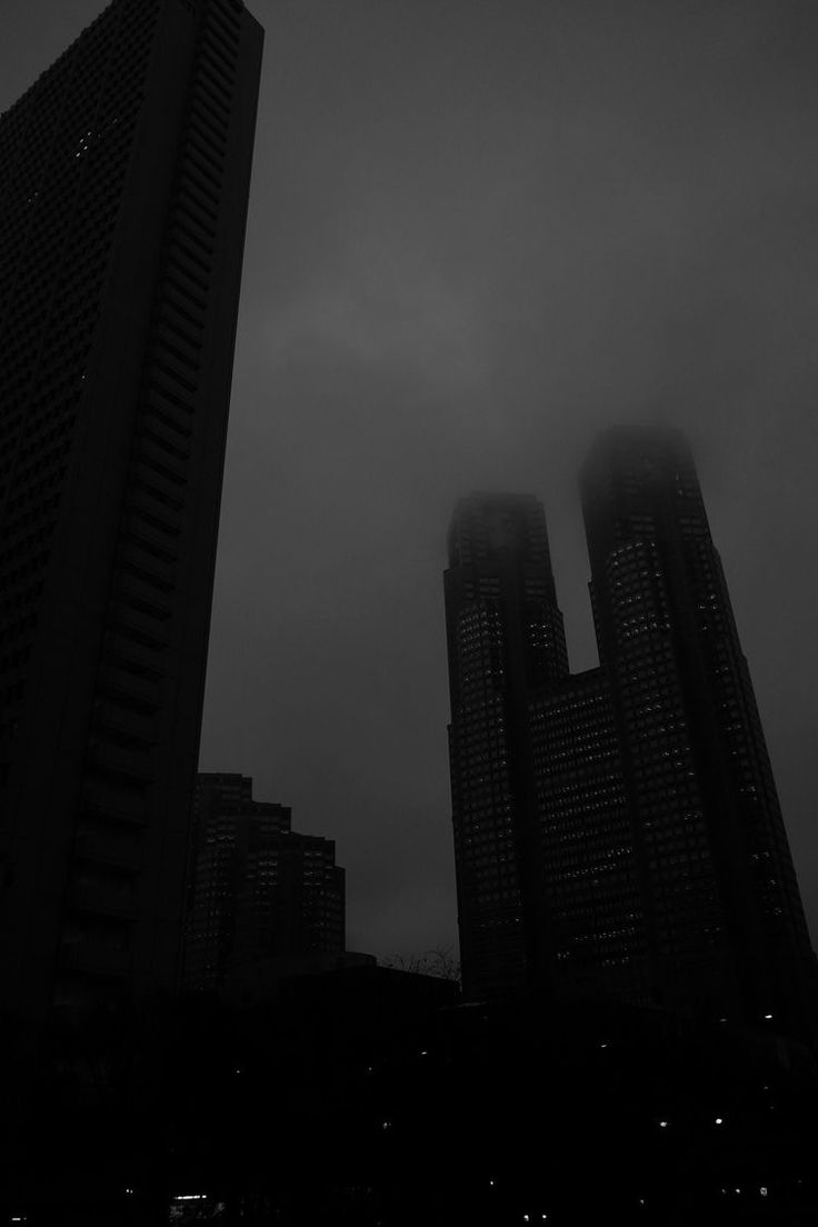 black and white photo of skyscrapers with fog in the air on a cloudy day