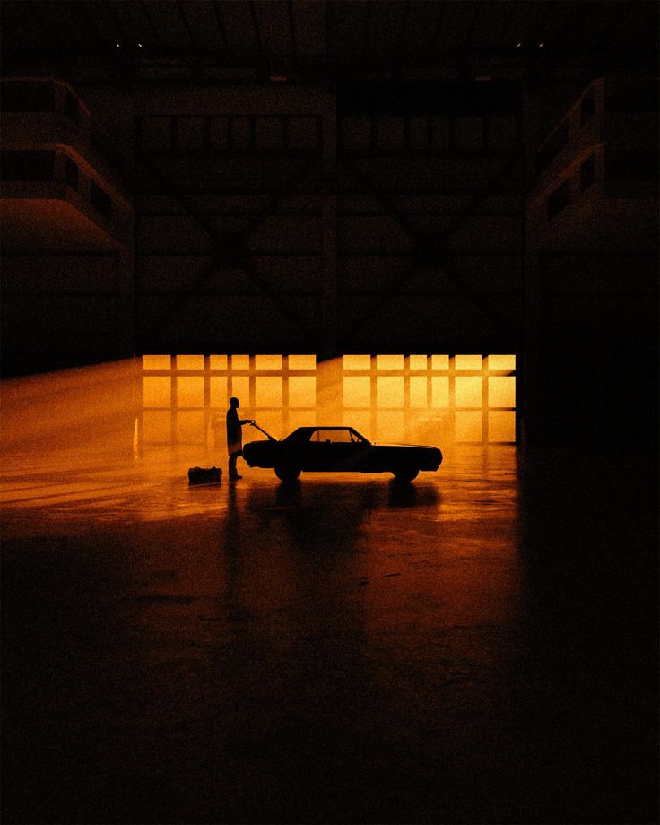 a car is parked in an empty parking garage at night with the light shining on it