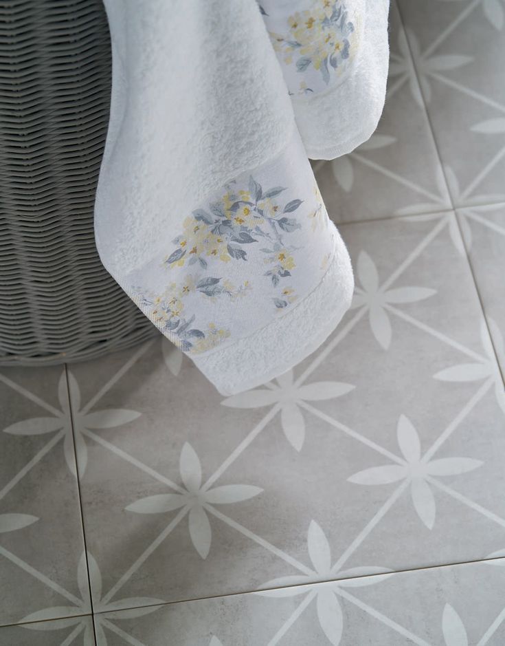 towels hanging on the side of a basket next to a towel rack with yellow flowers