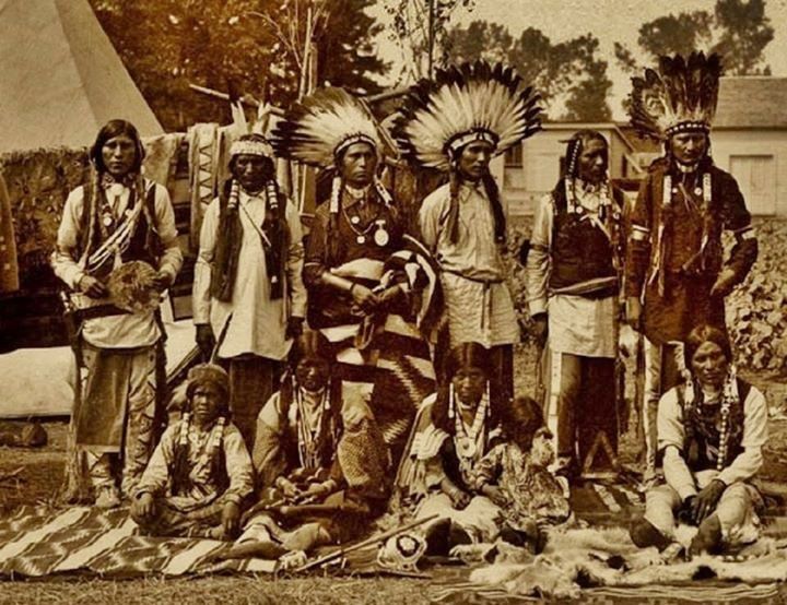 an old photo of native american indians posing for a group shot in front of a teepee