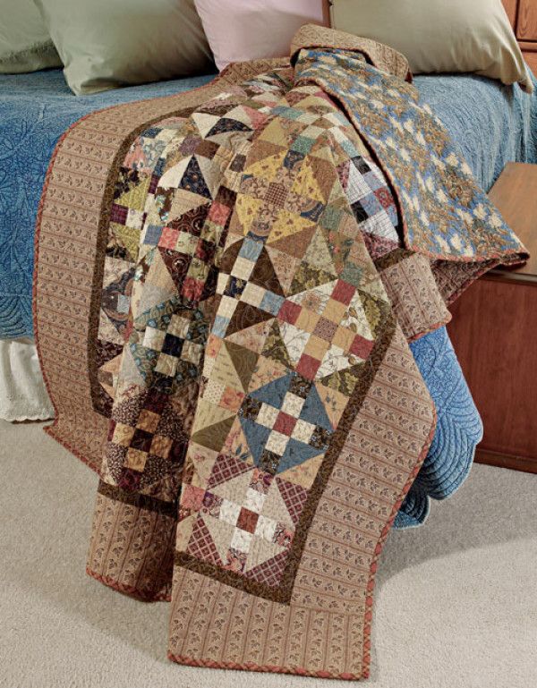 a bed topped with lots of pillows and quilts on top of each other next to a night stand