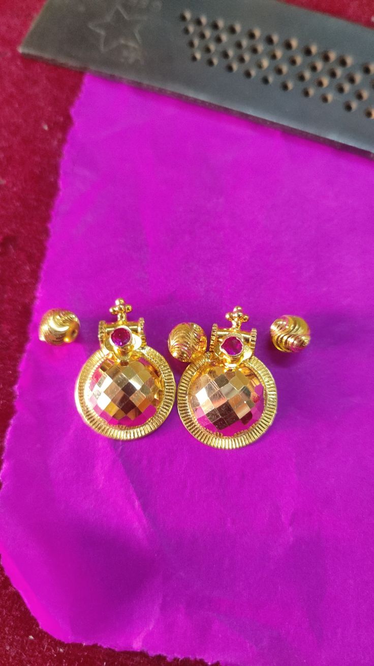 three pairs of earrings sitting on top of a purple cloth