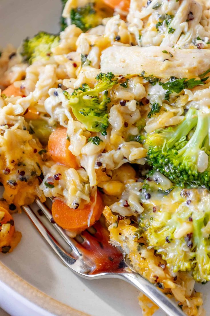 a white plate topped with broccoli, carrots and other vegetables next to a fork