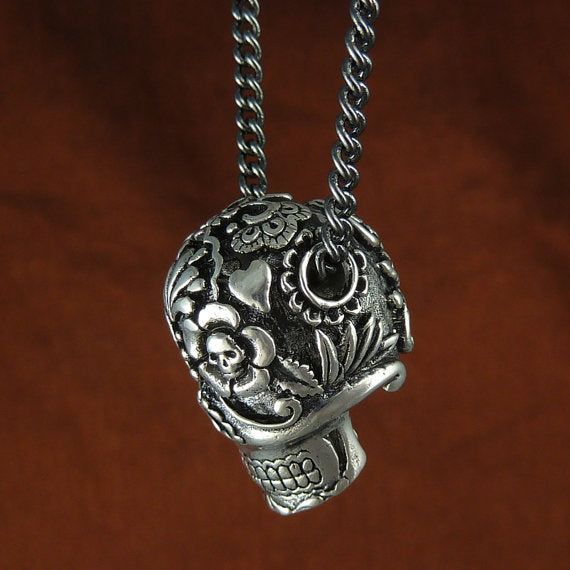 Day of the Dead Sugar Skull Necklace A beautifully detailed Dia de Los Muertos Sugar Skull pendant necklace. Hand carved and cast in the finest white bronze, the skull is thickly silver plated and then oxidized to give it a fantastic aged look. The stunning detail includes two tiny skulls in the skull's eyes and a large rose on the back. Each tooth is perfectly carved, as are the rose and the floral design behind the jaw. Available on a Gunmetal or Antique Silver curb chain. Skull pendant is 1" Gothic Silver Necklace With Skull Print, Nickel-free Skull Jewelry For Day Of The Dead, Nickel Free Skull Jewelry For Day Of The Dead, Handmade Silver Necklace With Skull Shape, Hand Cast Skull Necklace As Gift, Hand Cast Skull Necklace For Gift, Symbolic Skull Jewelry With Oxidized Finish, Bohemian Sterling Silver Skull Jewelry, Skull-shaped Engraved Necklace For Gift