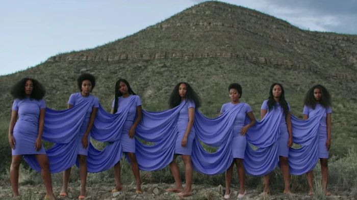 a group of women in blue dresses standing next to each other on top of a hill