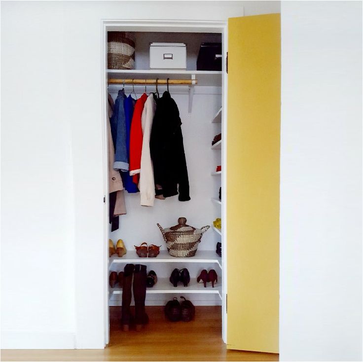 an open closet with shoes and clothes hanging on the wall, next to a yellow door