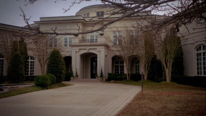 a large house with lots of windows and trees in front of the entrance to it