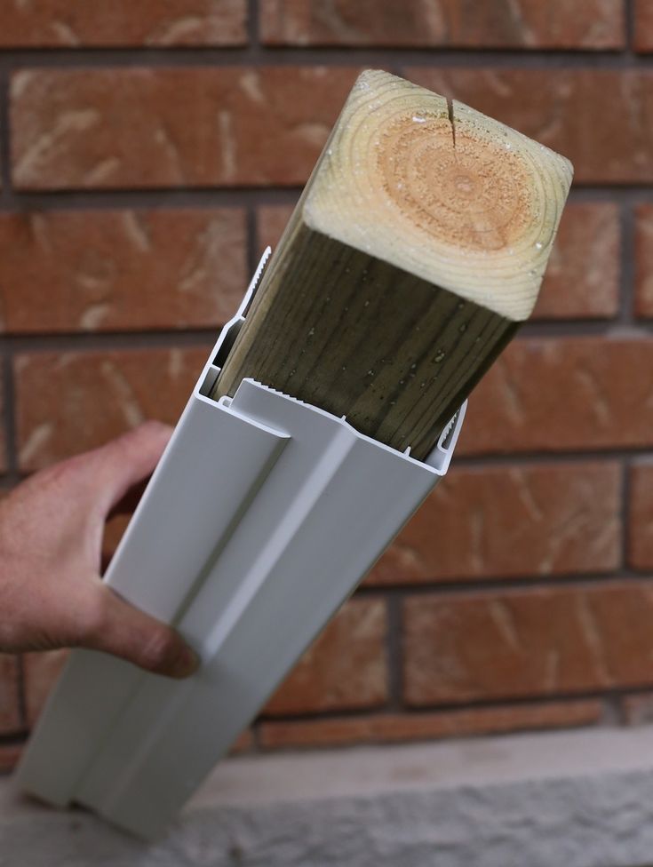 a person holding a paintbrush in front of a brick wall with the handle extended