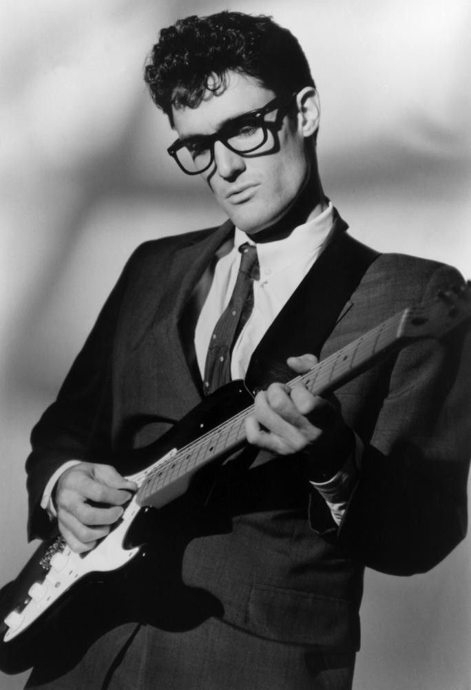 a man in a suit and tie playing an electric guitar