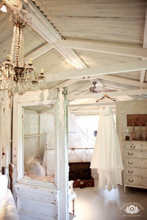 a bedroom with white furniture and a chandelier hanging from it's ceiling