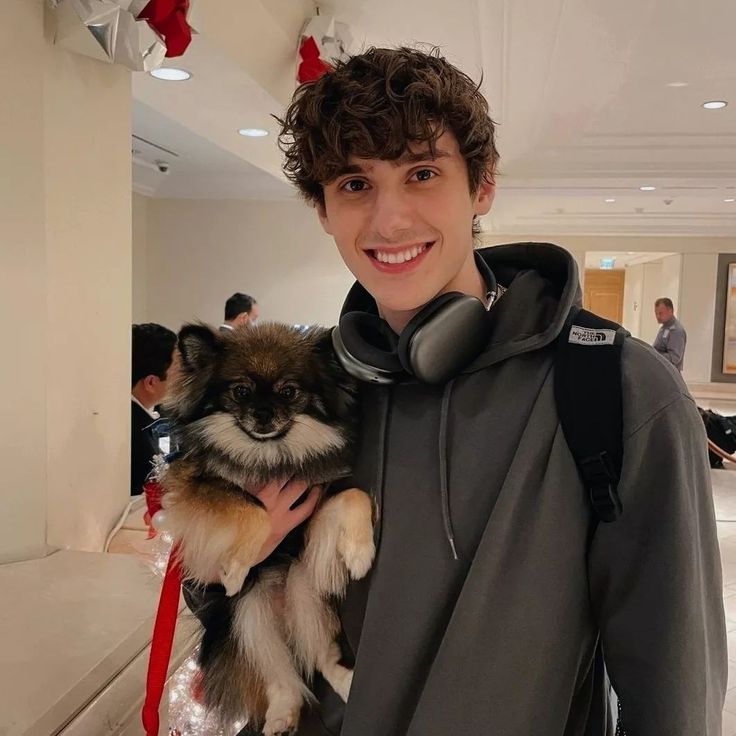 a young man holding a small dog in his arms