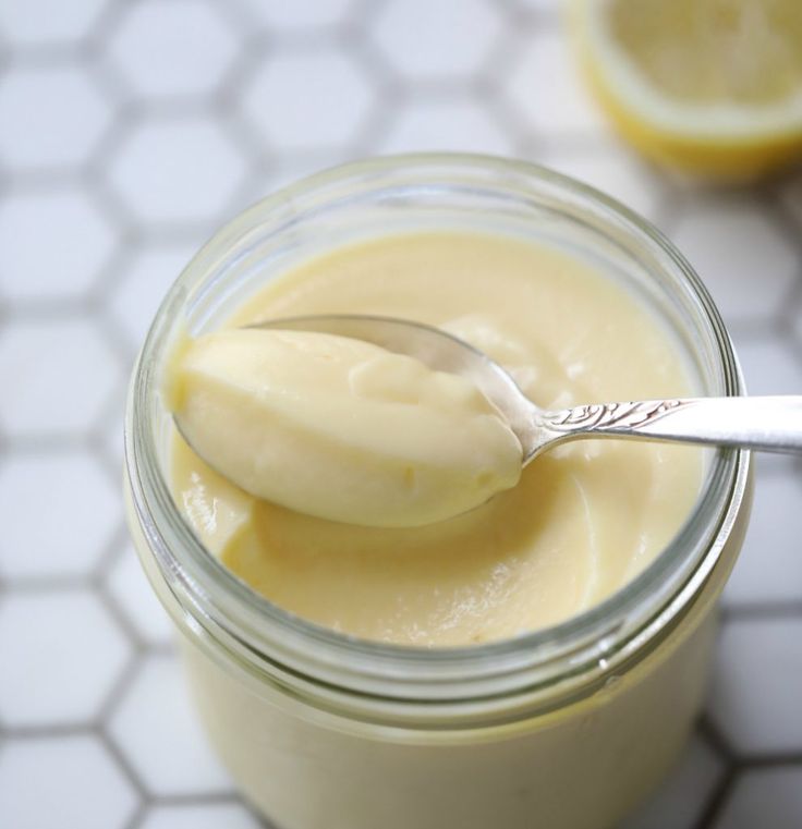 a spoon in a jar filled with yogurt on top of a tiled table