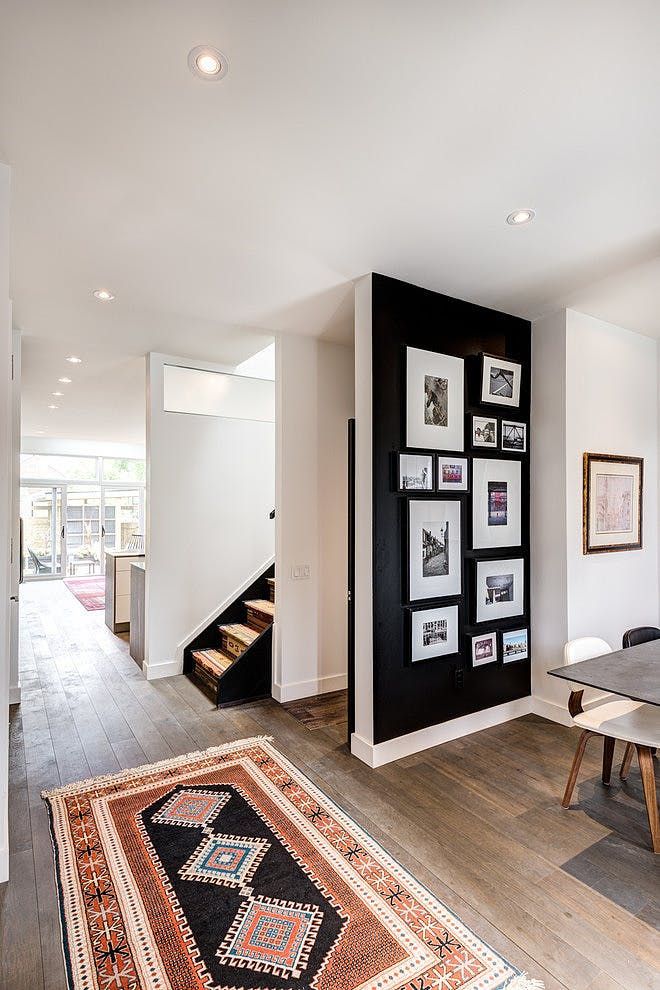 a dining room table with chairs and pictures on the wall behind it in front of a staircase