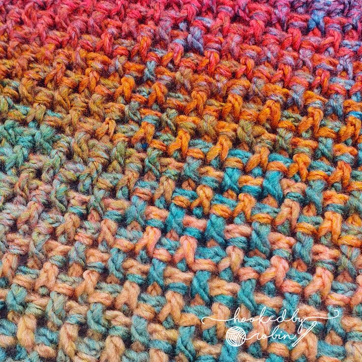 a multicolored crocheted blanket is shown in close up on the surface