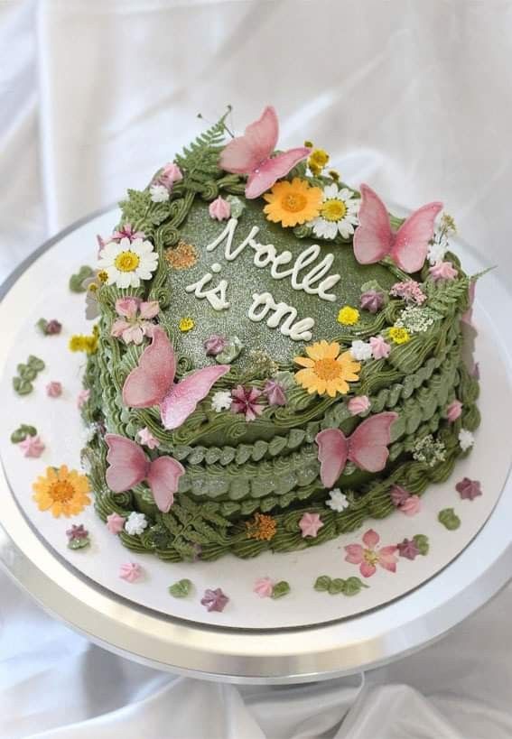 a green cake with flowers and butterflies on it that says no one is home in the center