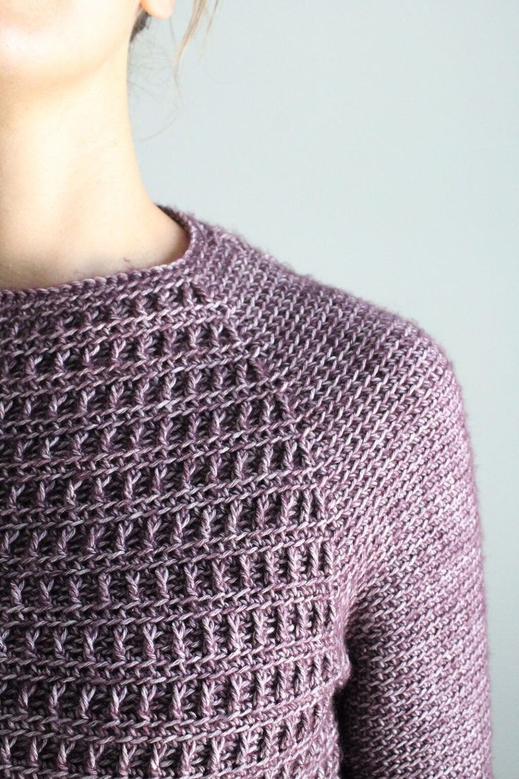 a woman wearing a purple sweater with crochet on it