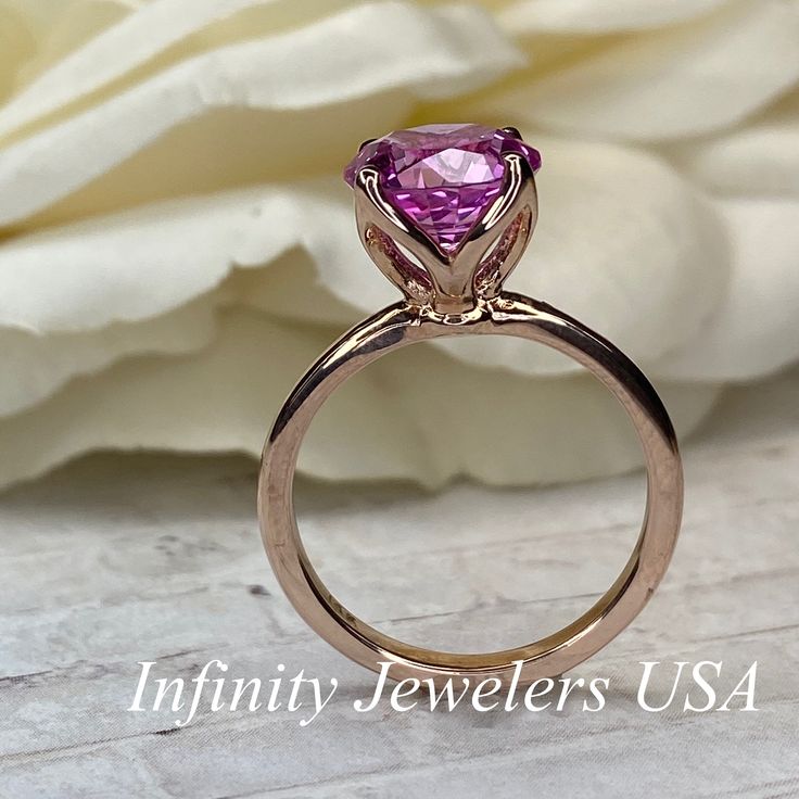 "This ring is a round cut lab created pink sapphire solitaire in 14k rose gold #6465 -Approximate total carat weight: 2.70ctw. diamond equivalent -Center Stone Size: approx. 2.70ct diamond equivalent -Center Stone Shape: round cut / 9 MM -Gem Type: lab created pink sapphire -Stone Clarity: VS2 -Stone Color: Medium Pink -Moh's Scale: 9 hardness -Metal Type and Purity: 14k rose gold -Setting: classic Tulip 4 Prong Setting -Stock Ring Size: 6 -Country of Manufacturing: USA (Michigan) For customizat Pink Gold Round Ruby Ring With Prong Setting, Pink Gold Ruby Ring With Prong Setting, Pink Ruby Ring With Accent Stones For Promise, Luxury Pink Amethyst Ring For Anniversary, Luxury Pink Amethyst Anniversary Ring, Pink Luxury Amethyst Ring For Anniversary, Pink Lab-created Ruby Ring With Brilliant Cut, Pink Brilliant Cut Lab-created Ruby Ring, Classic Pink Jewelry For Promise