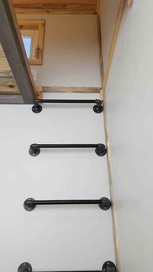 the stair rail is made from metal and has three black bars on each side, along with an open door