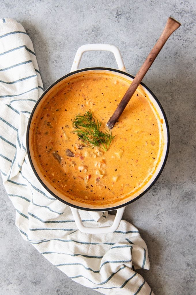 a pot filled with soup on top of a counter next to a wooden spoon and napkin