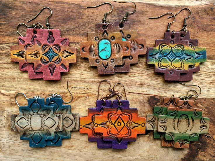 four different colored wooden earrings with designs on them