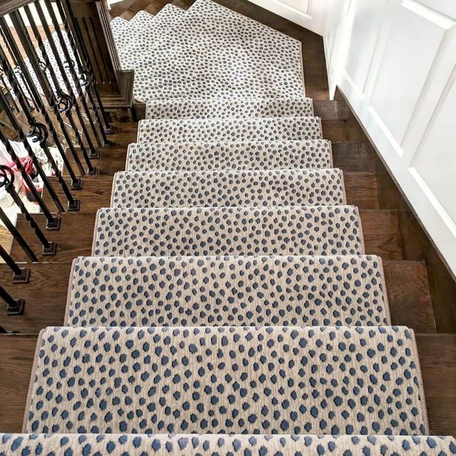 a set of stairs with blue and white rugs on the bottom, and black handrails