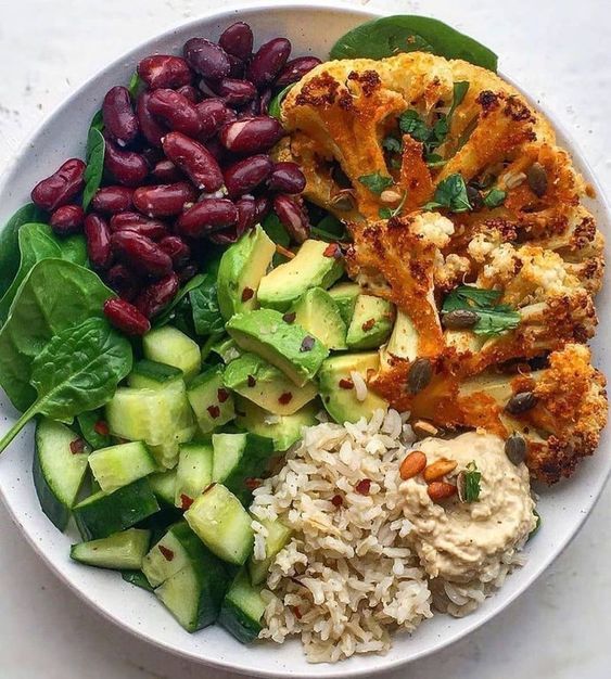 a white plate topped with rice, beans and veggies next to other foods