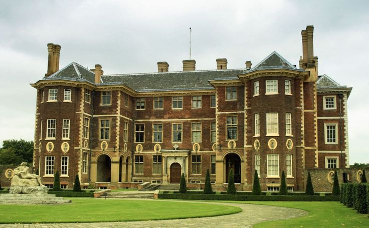 a large brick building sitting on top of a lush green field next to a fountain