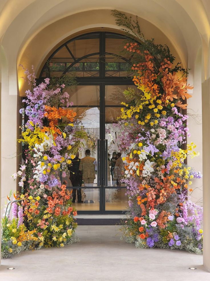 the entrance to a building is decorated with colorful flowers and greenery on both sides