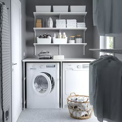 a washer and dryer sitting in a room next to each other with shelves on the wall