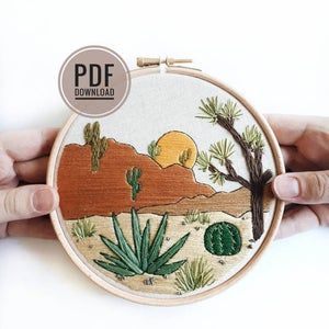 a hand embroidered desert scene with cactus trees