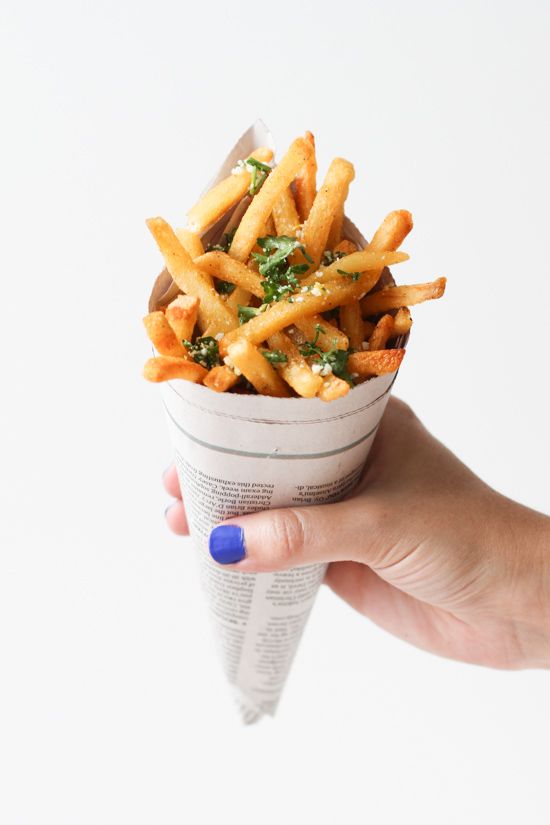 a hand holding a cup filled with french fries