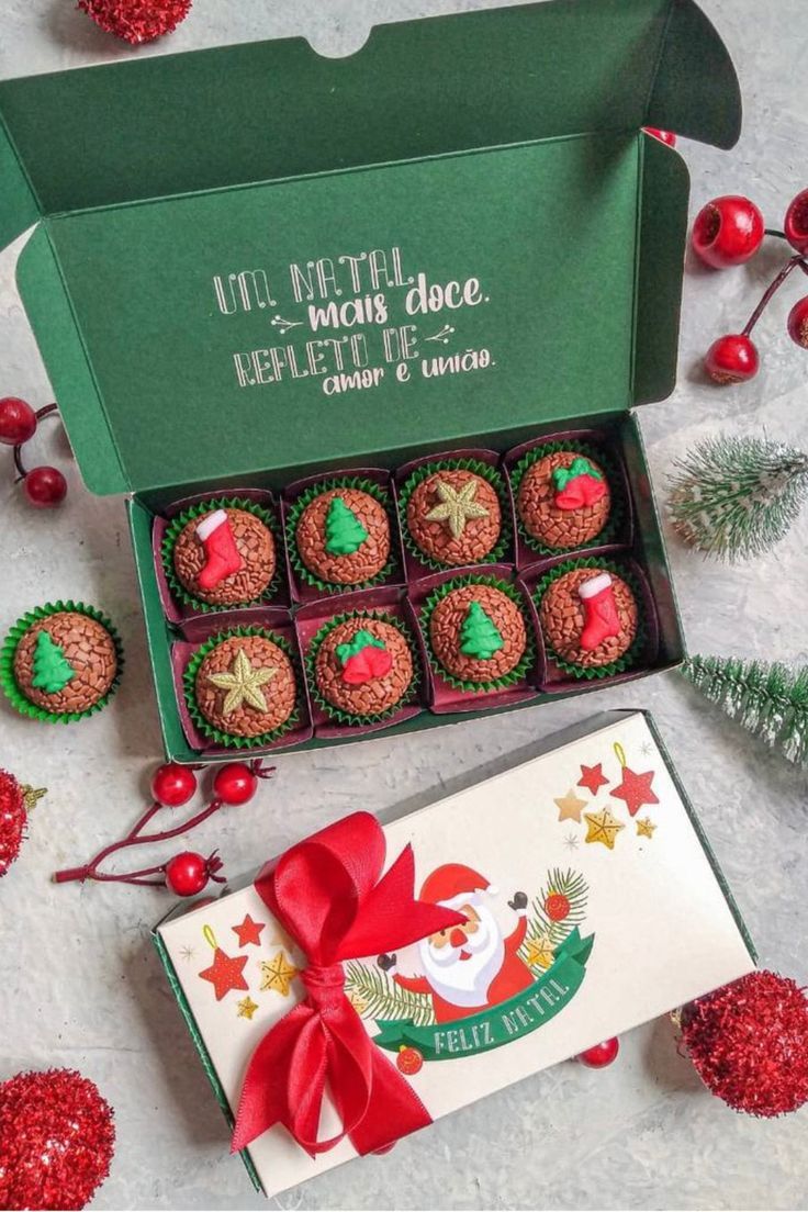 twelve christmas treats in a green box with red bows and decorations around them on a table