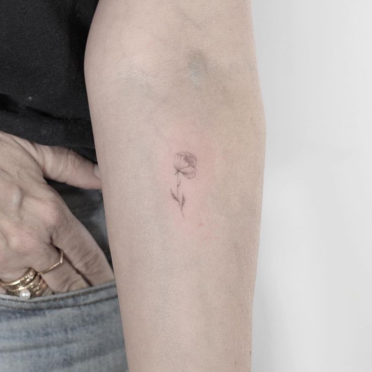 a person with a small flower tattoo on their arm