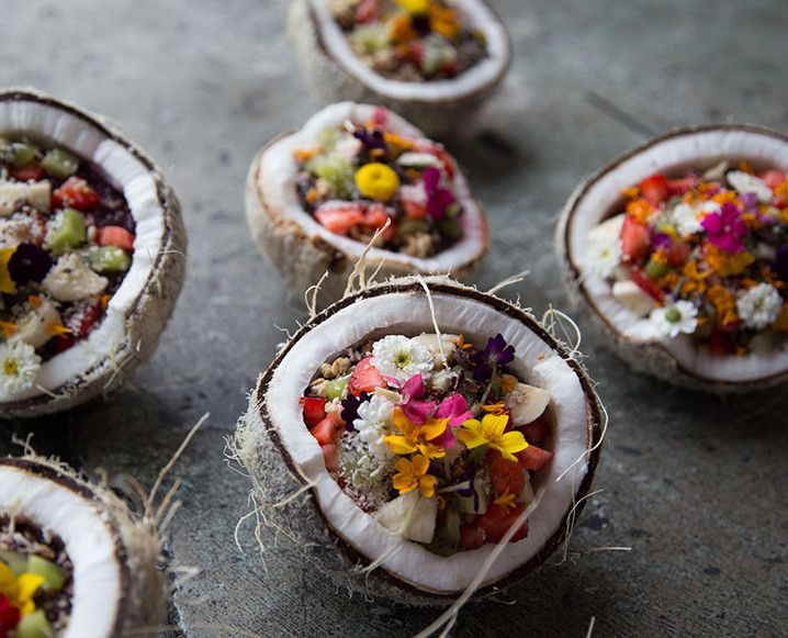 there are many different types of food in the coconuts on the table, and one is decorated with flowers