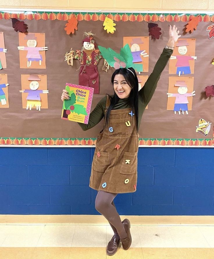 a girl is standing in front of a bulletin board holding her hands up and smiling