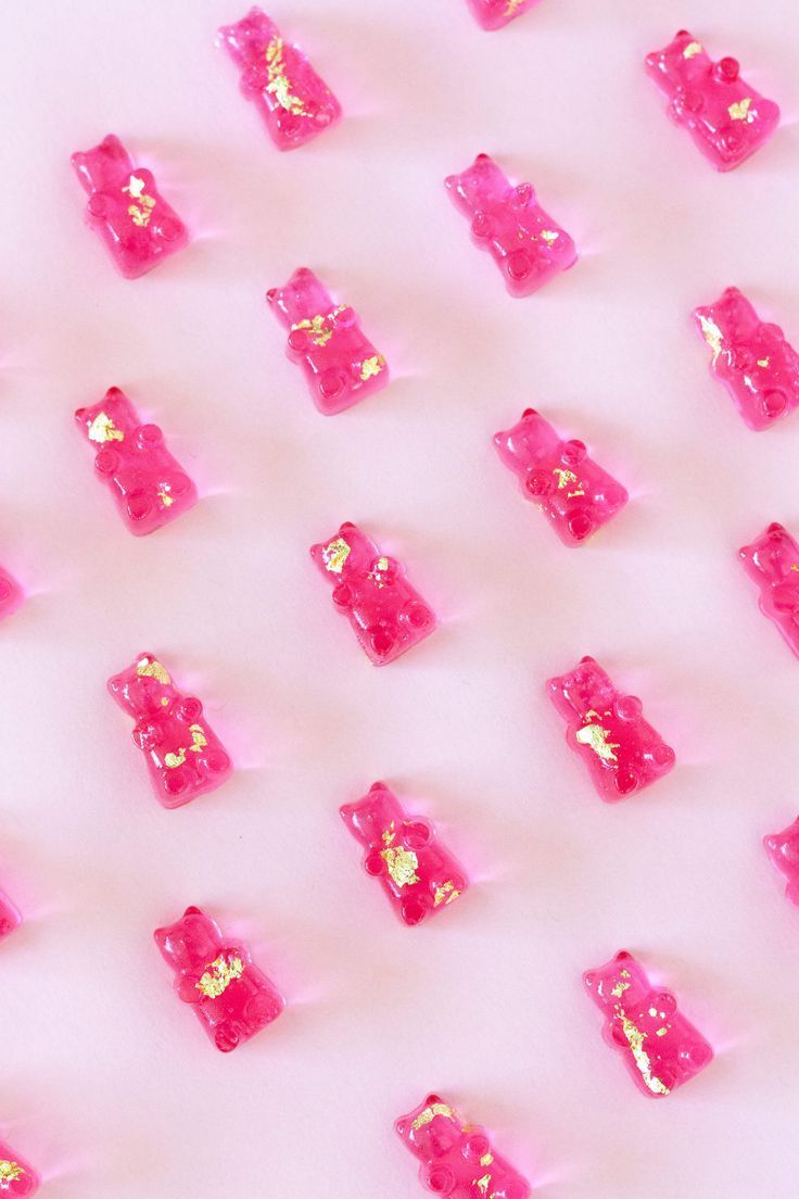 pink and gold glittered objects are arranged in rows on a white surface with light reflection