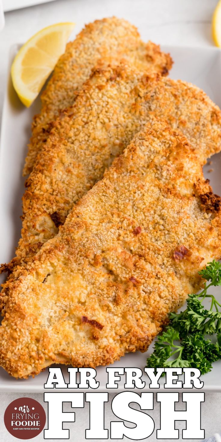 air fryer fish on a plate with lemons and parsley next to it