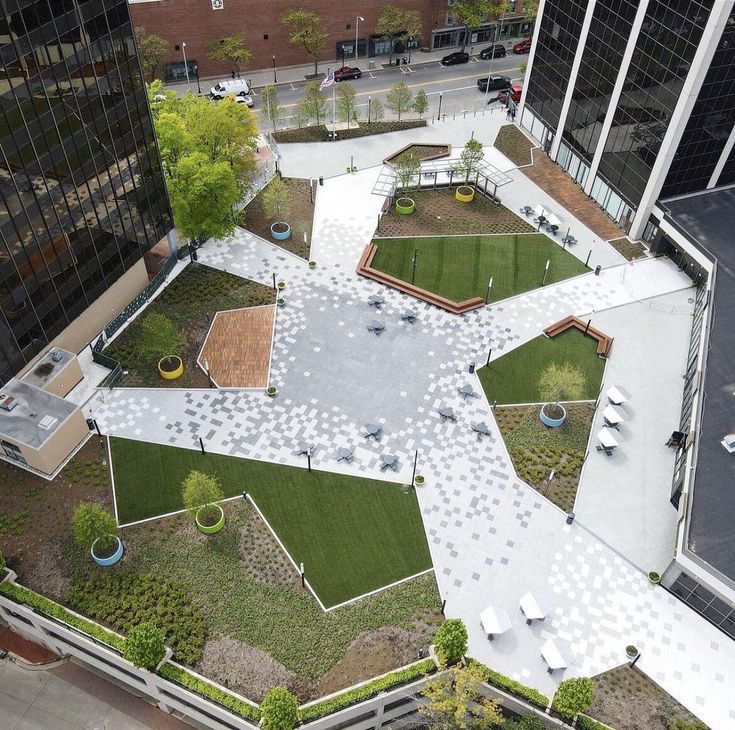 an aerial view of a green roof with benches and tables in the center, surrounded by tall buildings