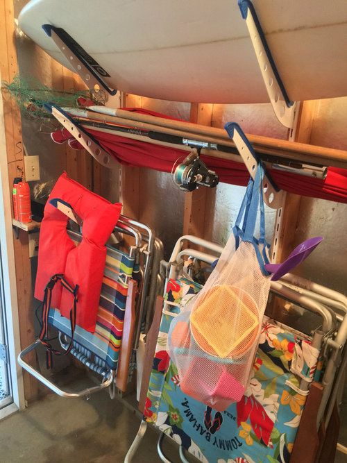 two surfboards are hanging on the wall next to some beach chairs and umbrellas