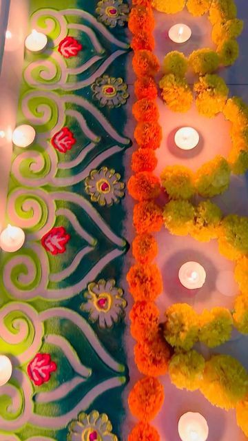 two rows of lit candles sitting on top of a table covered in flowers and leaves