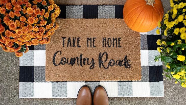 a welcome mat with the words take me home country roads on it next to flowers and pumpkins