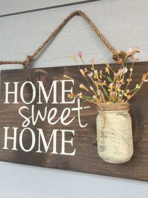 a wooden sign that says home sweet home with flowers in a mason jar hanging on the wall