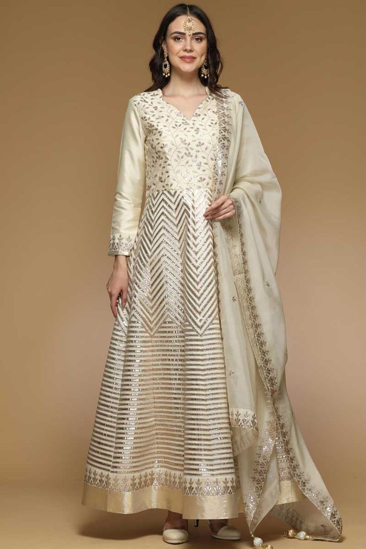 Featuring beautiful embroidery, this Cream Taffeta Silk Anarkali Suit Which will make you absolutely astoundingly gorgeous and that will be least interesting thing about you. This Sweetheart neck and Full Sleeves clothing designed with zari and gota patti work.Completed with  Santoon Churidar in Cream Color with Cream Chiffon Dupatta. Dupatta designed with Zari Work.This Anarkali Suit can be customised up to size 68 Inches around the Bust.Slight color variation may occur due to photographic reasons. Silk Anarkali Suits, Gota Patti Work, Angrakha Style, Silk Anarkali, Indian Salwar Kameez, Kurti Designs Party Wear, Cream Silk, Zari Work, Anarkali Suit