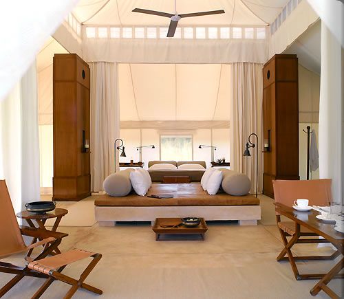 a living room filled with lots of furniture and white drapes on the windowsill