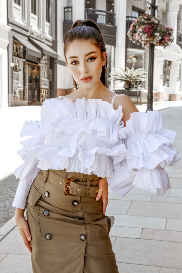 The kind of top that can take you from the party to the after-party, the After Hours shirt is a showstopping addition to any wardrobe. Tiers of ruffles give this blouse ample volume, while its thin, delicate straps offset the drama in a beautiful contrast. The long sleeve is finished with a bold cuff, and the off-the-shoulder design shows off those beautiful bare shoulders. #ruffleblouse #ruffletop #whiteblouse #shirt #blousetop #whiteshirt #offtheshouldertop Petite Clothes, Ruffle T Shirt, Fashion Themes, Bare Shoulders, Ruffle Shirt, The Drama, After Hours, Denim Trousers, High Waisted Trousers