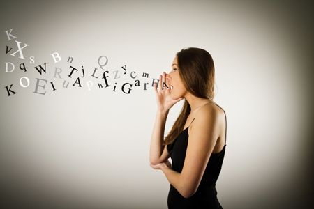 a woman standing in front of a white wall with letters written on the wall behind her