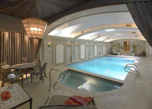 a large indoor swimming pool in the middle of a living room with chairs and tables