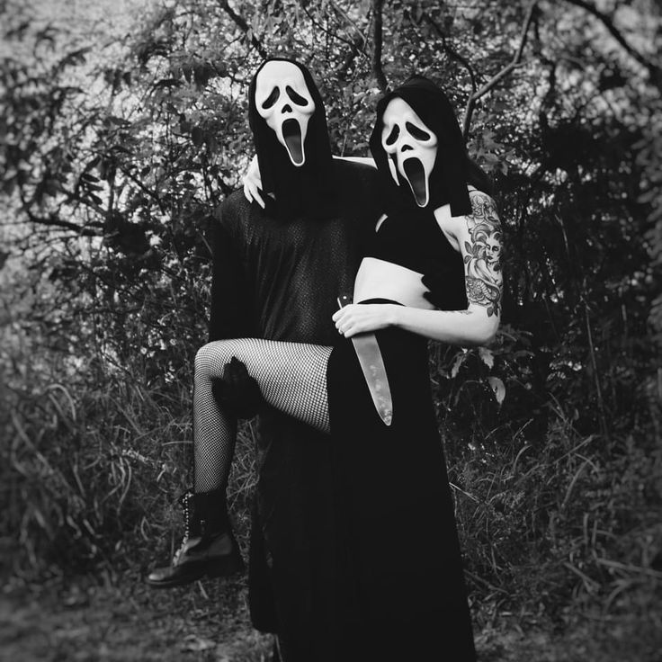 two people dressed in black and white are holding each other with their faces covered by masks