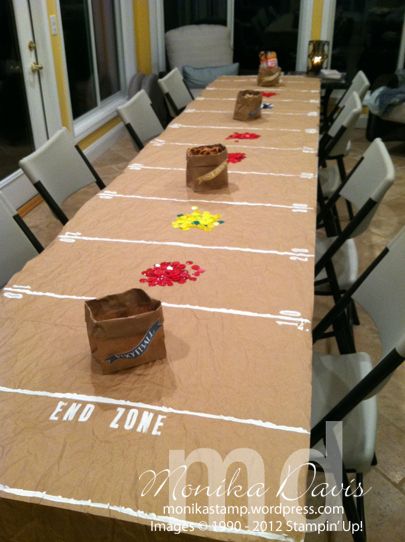 a long table is decorated with flowers and paper bags for the end zone to sit on