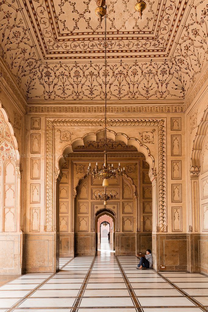 two people are sitting on the floor in an intricately decorated room with marble floors and walls